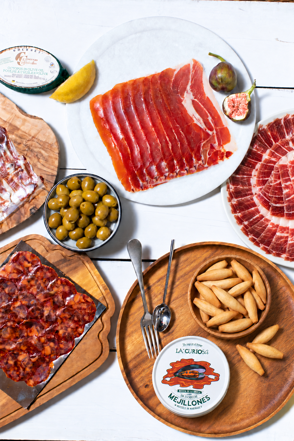 La Familia Tapas Selection with a circular arrangement of sliced Ibérico ham, Spanish charcuterie, olives, Picos Camperos and La Curiosa mussels.