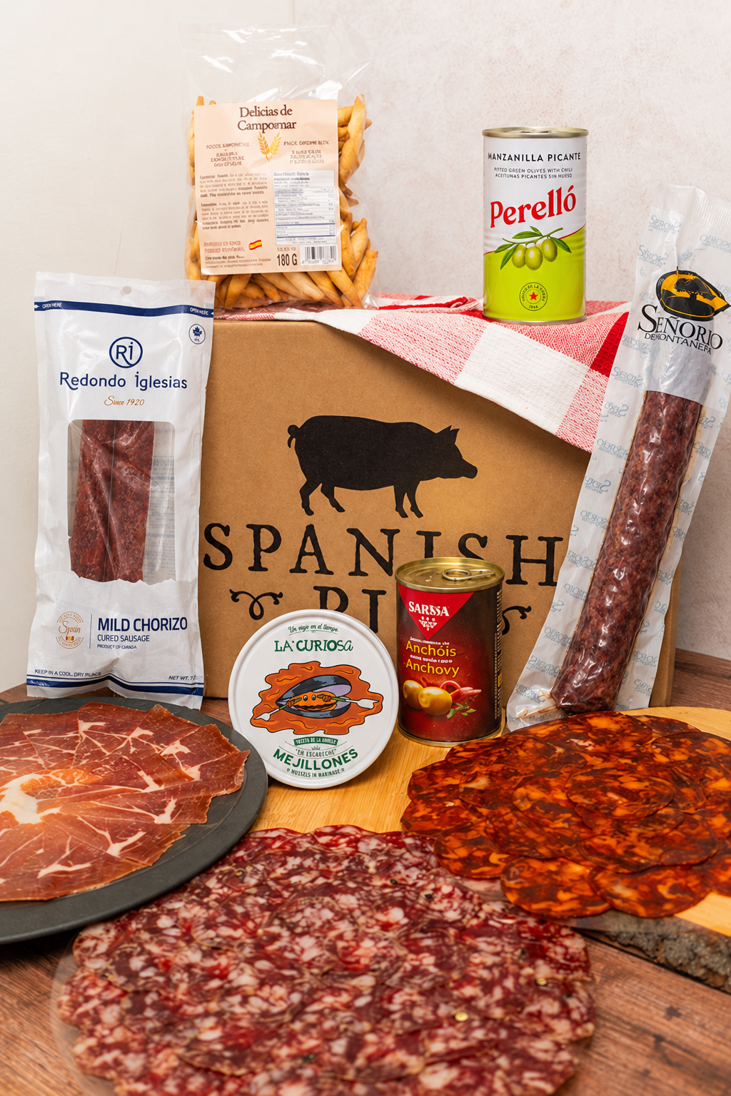 Tapas Box with Señorío de Montanera salchichón vela, standard Redondo Iglesias chorizo, La Curiosa mussels, Perelló olives, Serrano ham, sliced charcuterie and Picos Camperos.